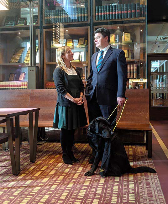 Associate Professor Paul Harpur with his guide dog Sean, speaking to a colleague Dr Kathy Ellem