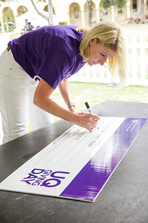 UQ staff member writing large novelty cheque. 