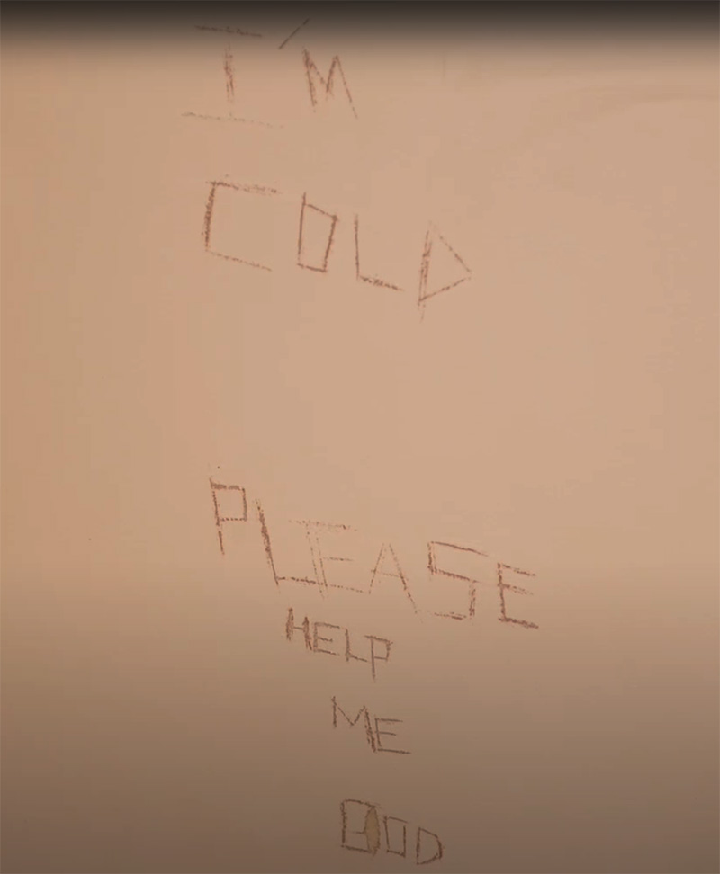 scratched writing on the wall of an isolation cell, 'I'm cold, please help me god'