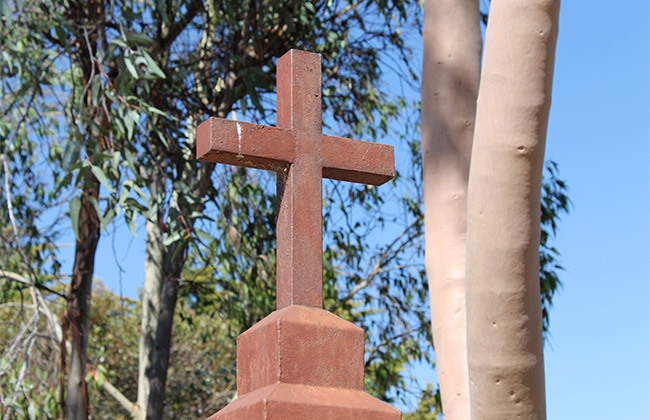 a Christian cross made of wood with gum trees in the background