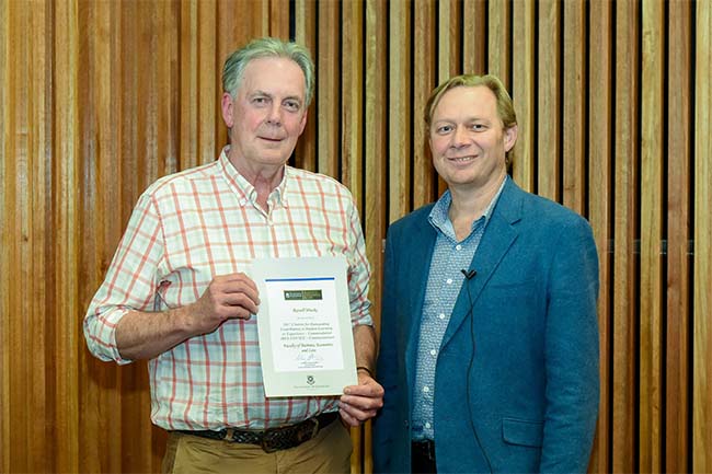 Russell Hinchy receiving an award from Andrew Griffiths