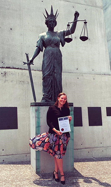 Keilin Anderson standing in front of a statue of Lady Justice