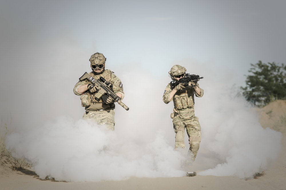 2 soldiers holding guns walking out of fog