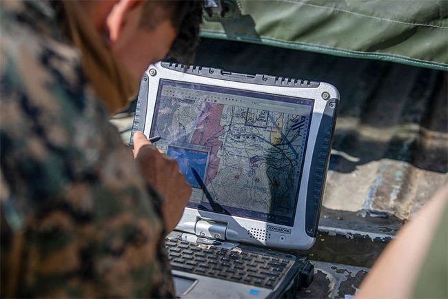 Marine looking over digital map on a portable computer in the field.in the field