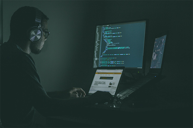 man coding on a computer in the dark.