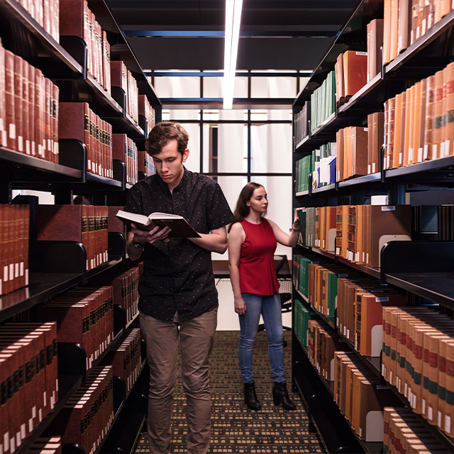 Two students searching through books in the Law Library