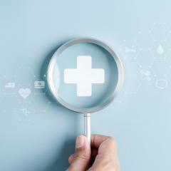 Hand holding a microscope over a medical cross