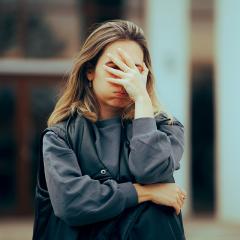 Woman hiding her face outside a building