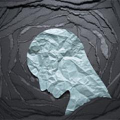 A paper tunnel of torn black paper with a white crumpled silhouette of a downturned head