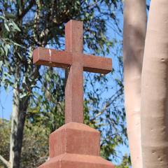 a Christian cross made of wood with gum trees in the background