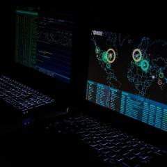 computer screens in dark showing world map data with cyrberattacks