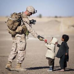 Soldier handing red ball to 2 children