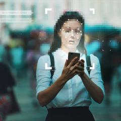 Woman is a crowd with a blurred face being digitally tracked through her mobile phone.