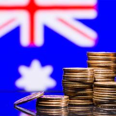 Gold coins stacked up in front of an Australian flag