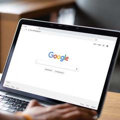 Person typing on Google search engine on laptop