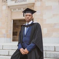 2025 UQ Graduate Alfred Brownell stands in front of the Forgan Smith Building