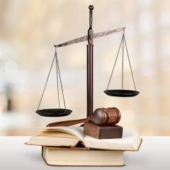 A small "scales of justice" with a gavel resting on an open book.