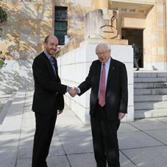 Associate Professor Jonathan Crowe and Sir Anthony Mason shaking hands outside the Forgan Smith Building