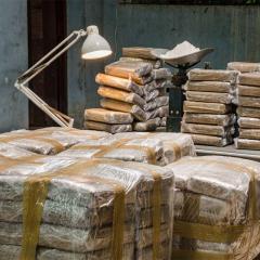 plastic wrapped bundles of cocaine in a concrete warehouse