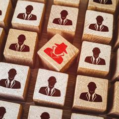 wooden blocks with a red spy silhouette among black businessperson silhouette 
